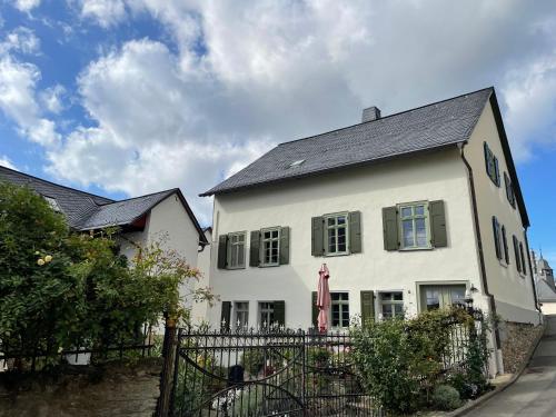 a white house with a black roof and a fence at Gut Bunt Ferienhaus in Runkel