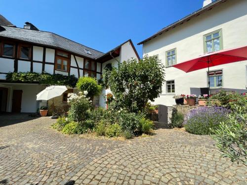 a house with an umbrella and a brick driveway at Gut Bunt Ferienhaus in Runkel