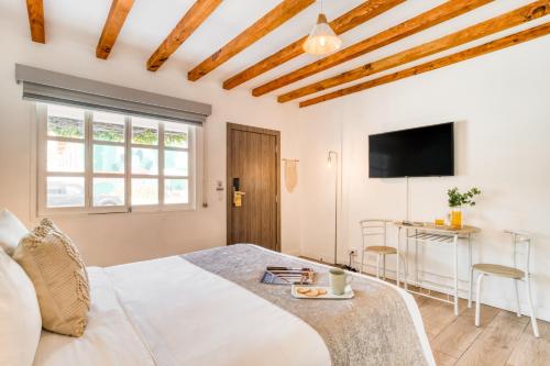 a white bedroom with a bed and a tv at Beach House by ULIV in Ensenada