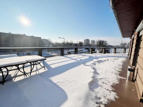 a snow covered deck with tables and benches on a bridge at Symfonia in Piotrków Trybunalski
