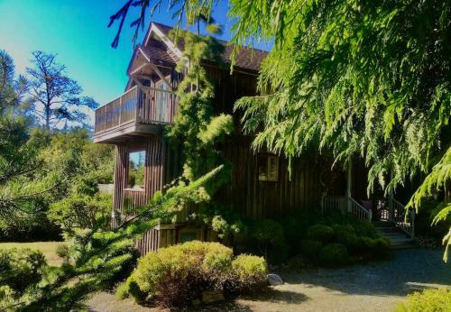 a log cabin with a balcony and a tree at French Beach House Shirley BC in Shirley