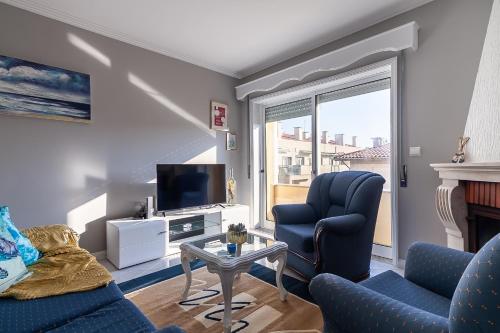 a living room with two chairs and a tv at VARANDAS DO MAR in Furadouro
