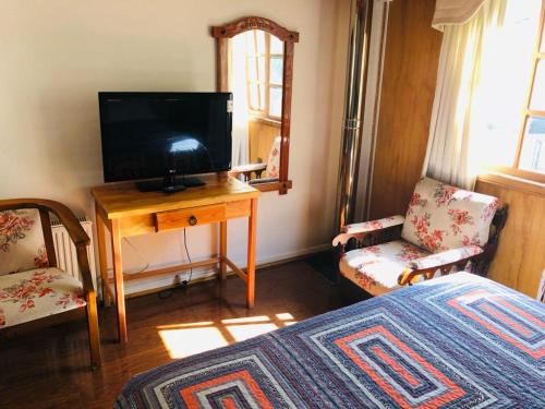 Dormitorio con TV y mesa con cama en Hostal Collins House en Temuco