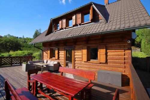 a wooden cabin with a bench on a deck at Chata Olesna in Olešná