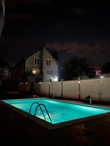 a swimming pool at night in front of a fence at Apartman Ms in Jajinci