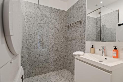 bagno bianco con lavandino e doccia di De Meir & Opera Urban Elegance Apt ad Anversa