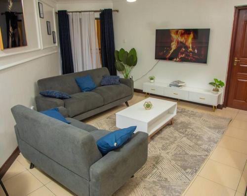 uma sala de estar com dois sofás e uma mesa de centro em Madaraka 2 Bed apartment with Rooftop pool. em Nairobi