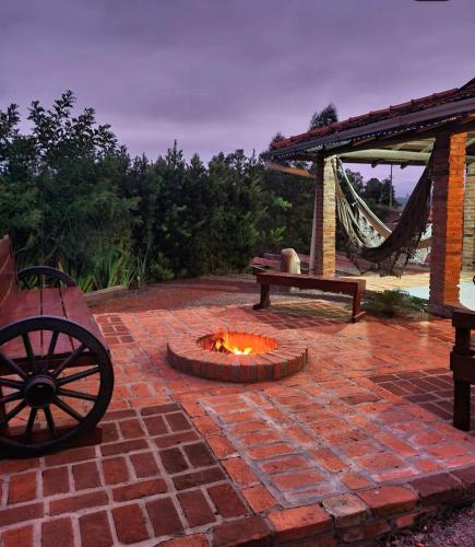 a brick patio with a fire pit and a bench at Recanto do Vento 