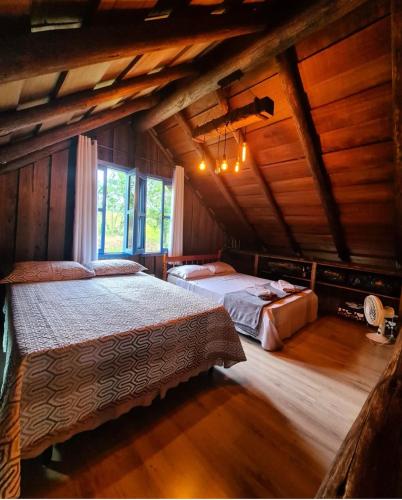 a bedroom with two beds in a wooden cabin at Recanto do Vento 