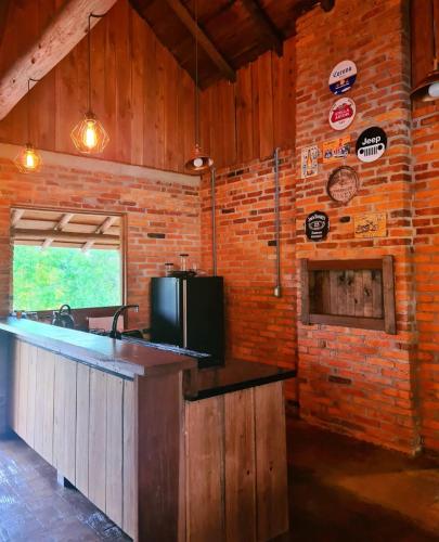 a kitchen with a counter and a brick wall at Recanto do Vento 