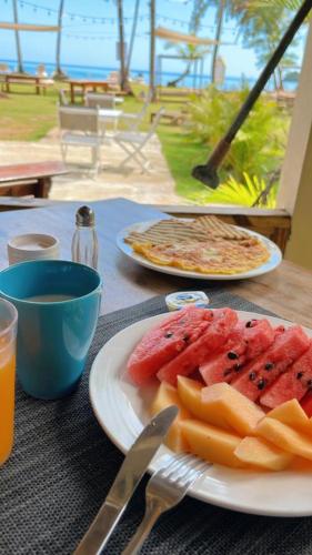 a table with two plates of food and watermelon and cheese at Casa Grande Hotel Restaurant in Las Terrenas