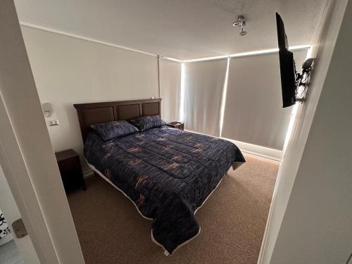 una camera da letto con un letto con un piumone blu di Depto Completo a 15 minutos del aereopuerto y frente al Mall a Santiago