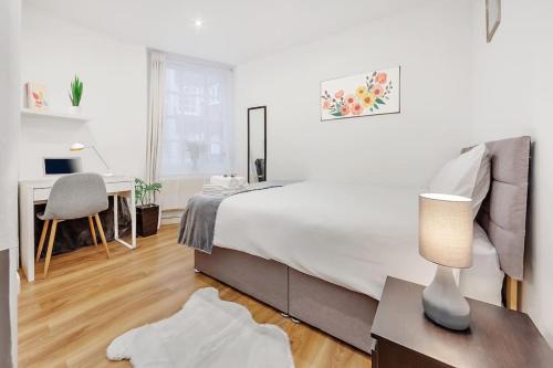 een witte slaapkamer met een bed en een bureau bij Regent's Park apartment in Londen