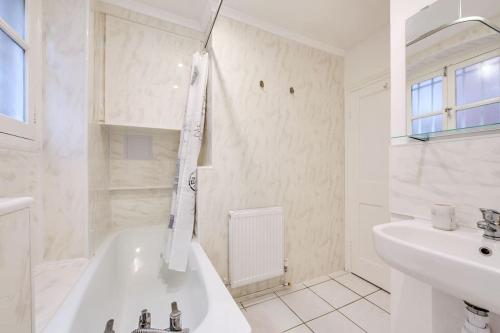 een witte badkamer met een bad en een wastafel bij Regent's Park apartment in Londen