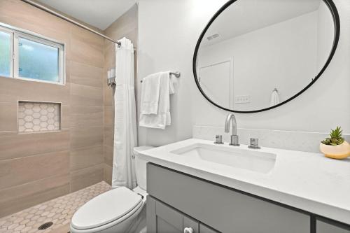W białej łazience znajduje się umywalka i lustro. w obiekcie Redbud Rhythms Retreat w mieście Austin