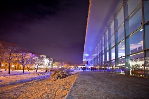 a snow covered sidewalk next to a building at night at Piastun SPA&Wellness Krynica-Zdrój in Krynica Zdrój
