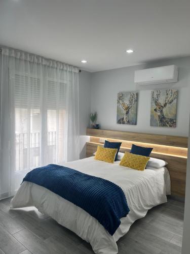a bedroom with a large bed with blue and yellow pillows at Matallana 32 in Herencia