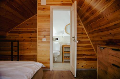 a bedroom with wooden walls and a bathroom with a toilet at Zenit Chalet Sohodol-Bran in Sohodol