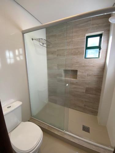 a bathroom with a toilet and a glass shower at Spazio Vital Apartments in Florianópolis