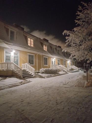 een groot geel huis met 's nachts sneeuw voor de deur bij Warkhaus Apartments Korpela in Varkaus