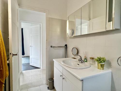 une salle de bain blanche avec un lavabo et un miroir dans l'établissement Fiorella's Cannes Oasis, à Cannes