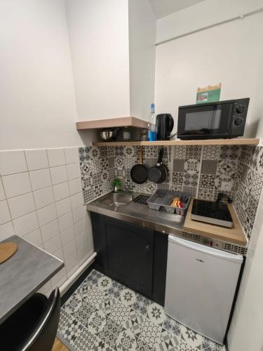 une petite cuisine avec une cuisinière et un micro-ondes dans l'établissement Studio Chaleureux proche gare, à Amiens