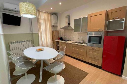 uma cozinha com uma mesa e cadeiras brancas e um frigorífico vermelho em Lemon House in the center Pesante em Sanremo