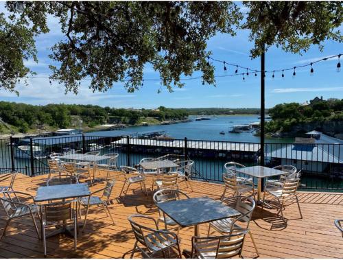a deck with tables and chairs and a view of a river at Lakeshore Haven in Spicewood