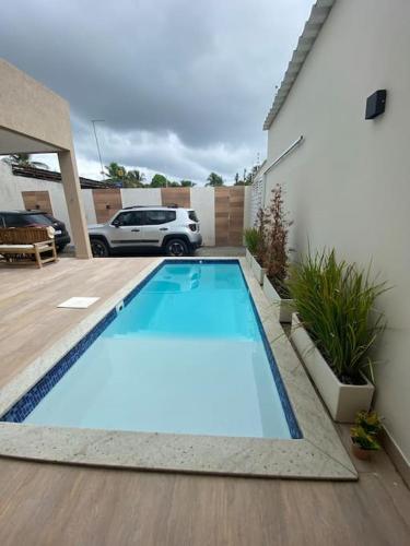 una piscina azul en un patio con coche en Guaibim House- Sua casa de praia en Guaibim