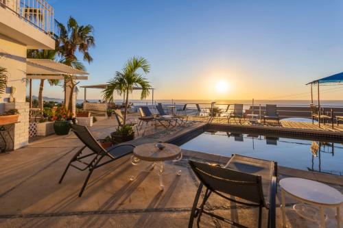 a patio with chairs and a pool and the ocean at MariaMar Suites in San José del Cabo
