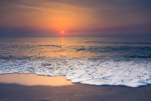 una puesta de sol sobre el océano con una playa de arena en Departamento Playa Bristol Casino en Mar del Plata