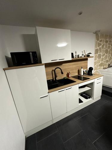 een witte keuken met een wastafel en een magnetron bij Msroom in Le Val-dʼAjol