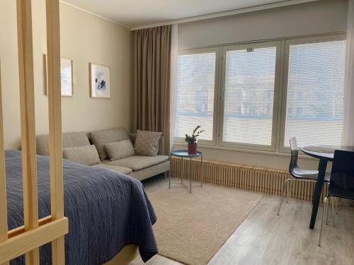 a bedroom with a bed and a couch and a table at Bright City Apartment with free Car Park and Wi-Fi in Vaasa