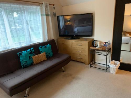 a living room with a couch and a flat screen tv at Broadwalk8 in Coltishall
