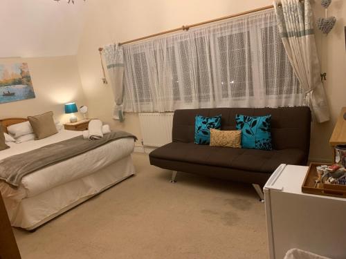a bedroom with a bed and a couch and a window at Broadwalk8 in Coltishall