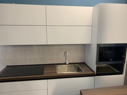 a kitchen with white cabinets and a sink and a microwave at Roxy House Trani in Trani