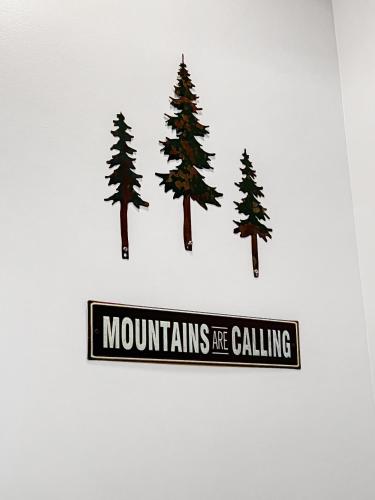 a sign that says mountains are calling with pine trees at Mammoth Overlook Of Yellowstone in Gardiner