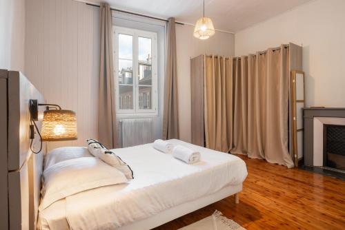 a bedroom with a white bed and a fireplace at Appartement spacieux et chaleureux coeur de ville in Chambéry