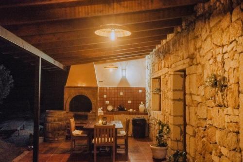 uma sala de jantar com mesa e cadeiras e uma parede de pedra em Beautiful Olive's cave house em Lomo de Arico
