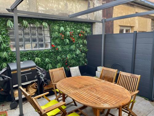 eine Terrasse mit einem Tisch und Stühlen sowie einer grünen Wand in der Unterkunft Bel Appartement terrasse privée à 5 minutes du métro in Romainville