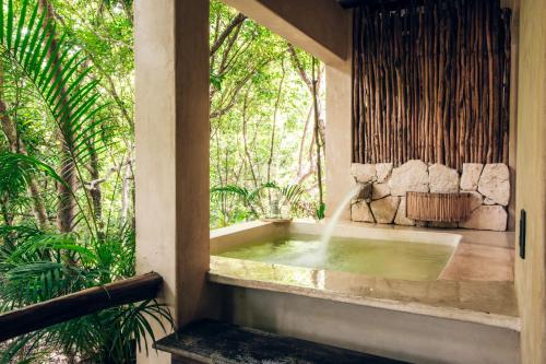 a bath tub with a fountain in a room with trees at Orchid House Tulum Jungle in Tulum