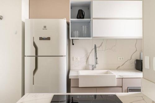 una cucina bianca con frigorifero e lavandino di Flat lindo e moderno a Belo Horizonte