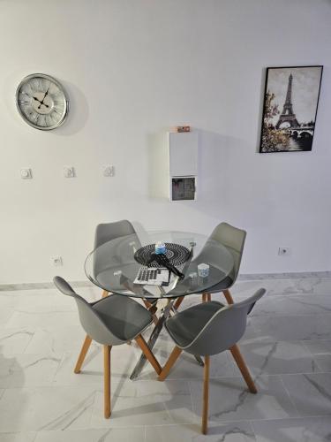 une table en verre avec deux chaises et une horloge sur un mur dans l'établissement T2 moderne, calme et entièrement rénové., à Béziers