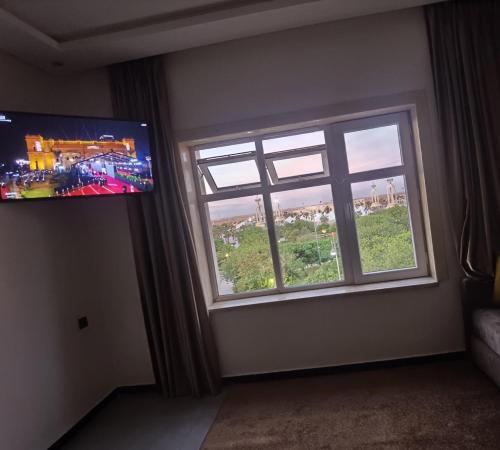 Habitación con ventana y TV de pantalla plana. en شقق مفروسة المشور, en Laayoune