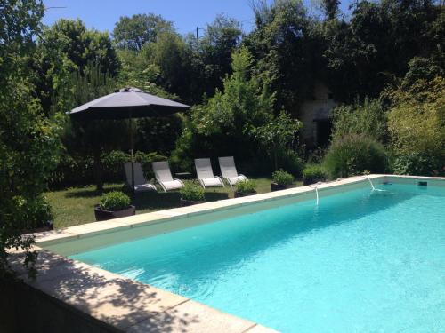 - une piscine avec 2 chaises et un parasol dans l'établissement L'Arcane Du Bellay, à Montreuil-Bellay