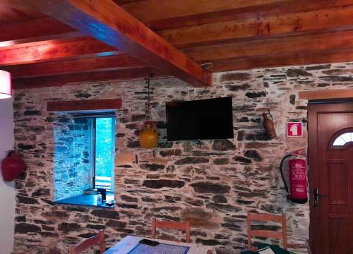a room with a stone wall with a television on it at Casa do Salgueirinho in Casal do Rei