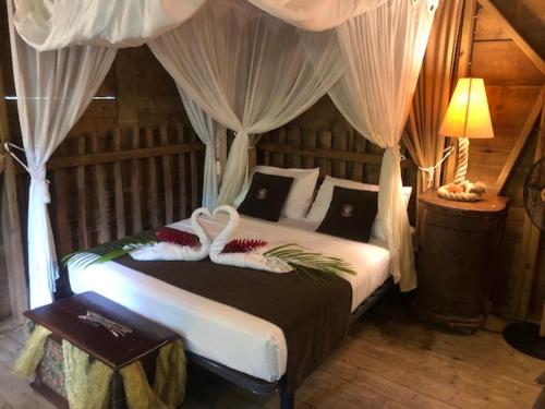 a bedroom with a bed with white sheets and a canopy at West Indies Cottage in Pointe-Noire