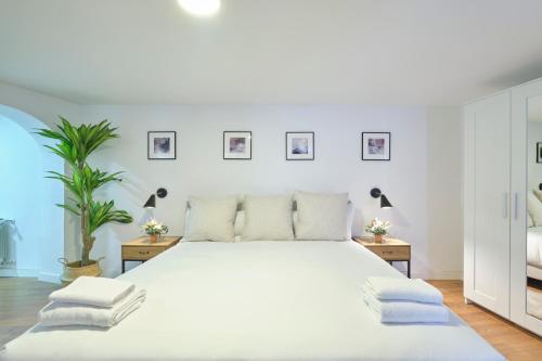 ein weißes Schlafzimmer mit einem großen weißen Bett und 2 Tischen in der Unterkunft Lovely Apartments - Increíble loft en el corazón de Madrid in Madrid