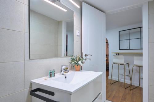 a white bathroom with a sink and a mirror at Lovely Apartments - Increíble loft en el corazón de Madrid in Madrid