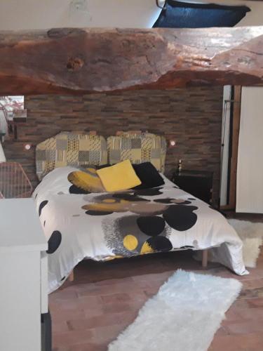 uma cama com um edredão e almofadas em Chambre d hôtes em Saint-Symphorien-dʼAncelles